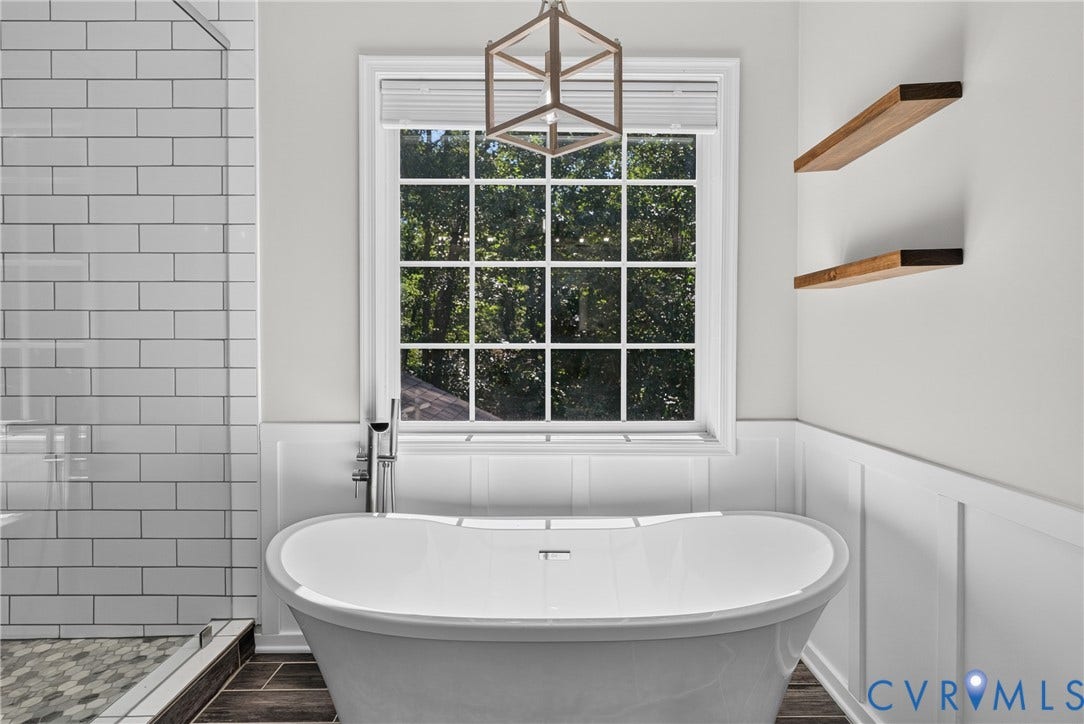 381 Shorewood Drive, Shorewood, Mineral, VA 23117 Freestanding tub with a chrome floor-mounted faucet, complemented by wainscoting and natural wood floating shelves