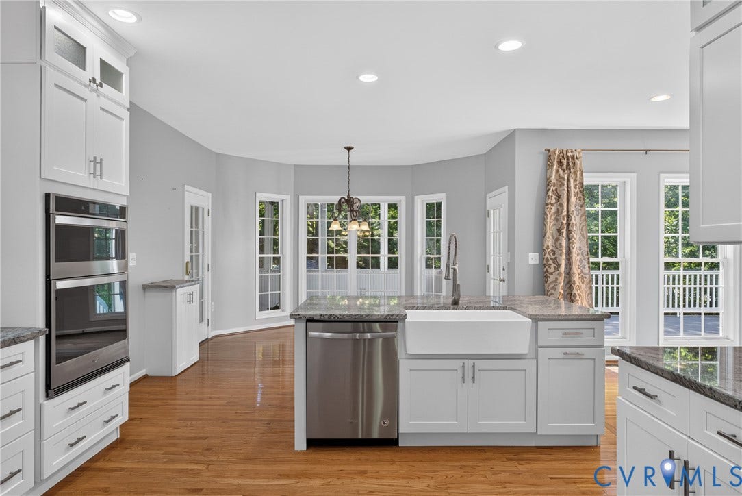 381 Shorewood Drive, Shorewood, Mineral, VA 23117 Kitchen featuring an island with a farmhouse sink and stainless steel dishwasher, double wall ovens, granite countertops, white cabinetry, and wood-finish flooring
