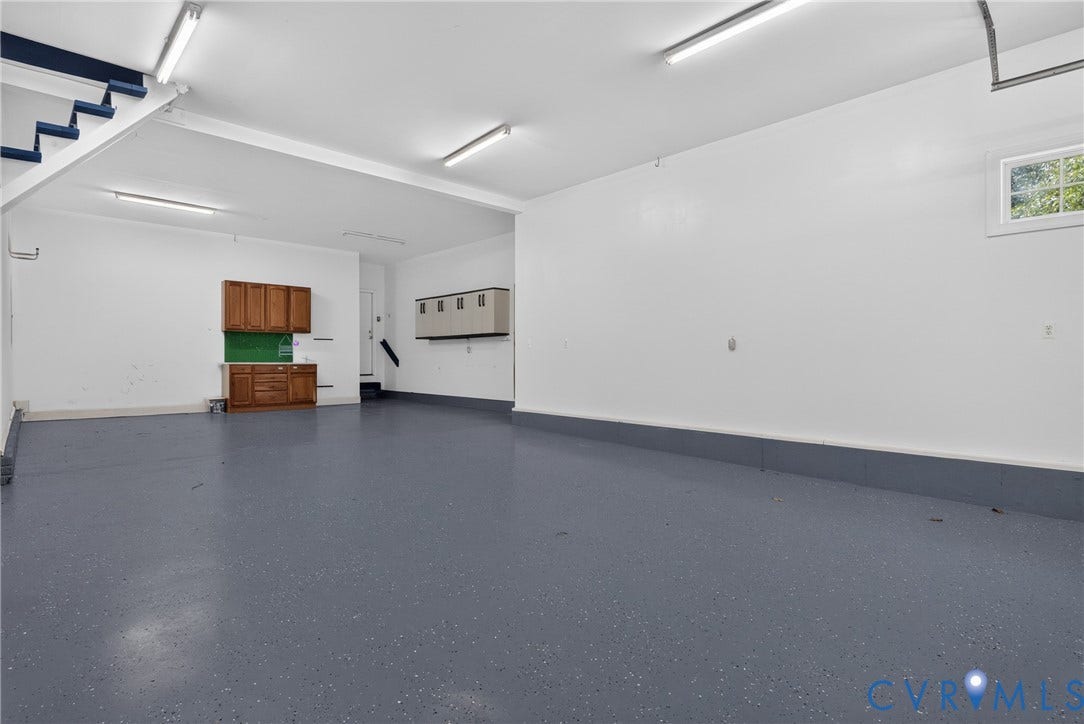 381 Shorewood Drive, Shorewood, Mineral, VA 23117 Spacious garage featuring a speckled gray epoxy floor, white walls, and bright overhead fluorescent lighting