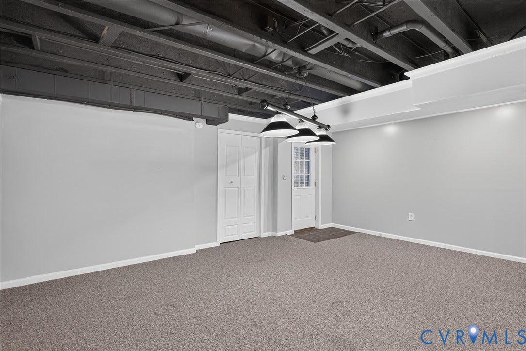 381 Shorewood Drive, Shorewood, Mineral, VA 23117 Spacious room featuring neutral carpeting, light gray walls, exposed painted ceiling joists, recessed lighting, and a white paneled door