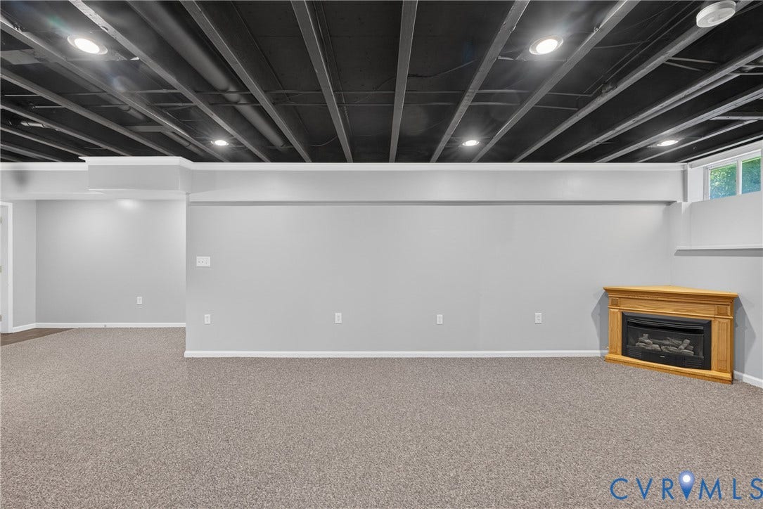 381 Shorewood Drive, Shorewood, Mineral, VA 23117 Expansive room featuring light gray walls, textured carpet flooring, and a corner fireplace with a light wood mantel