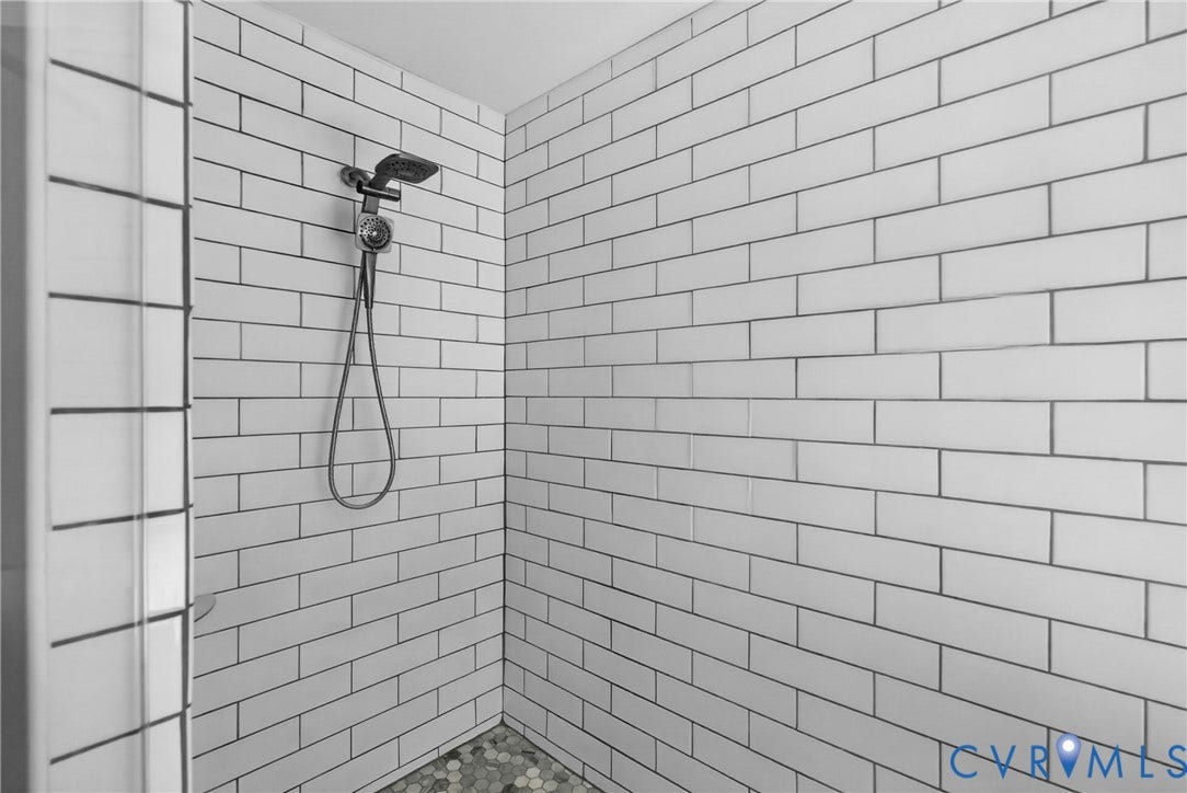 381 Shorewood Drive, Shorewood, Mineral, VA 23117 Shower stall with white subway tile walls, dark grout, a chrome showerhead, and pebble flooring
