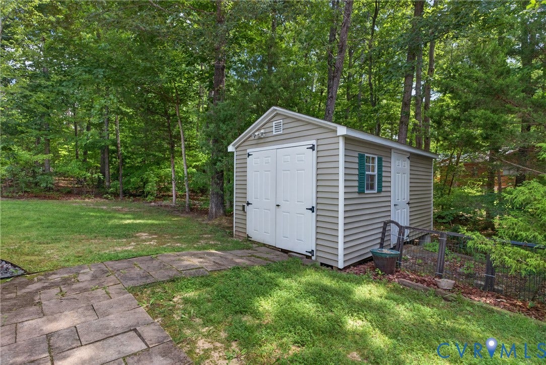 381 Shorewood Drive, Shorewood, Mineral, VA 23117 Backyard storage shed with beige siding, white double doors, and a side window with green shutters