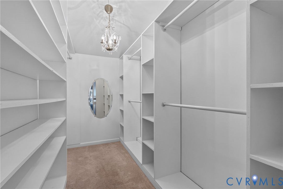 381 Shorewood Drive, Shorewood, Mineral, VA 23117 Spacious walk-in closet featuring extensive built-in shelving, hanging rods, an oval wall mirror, and a crystal chandelier
