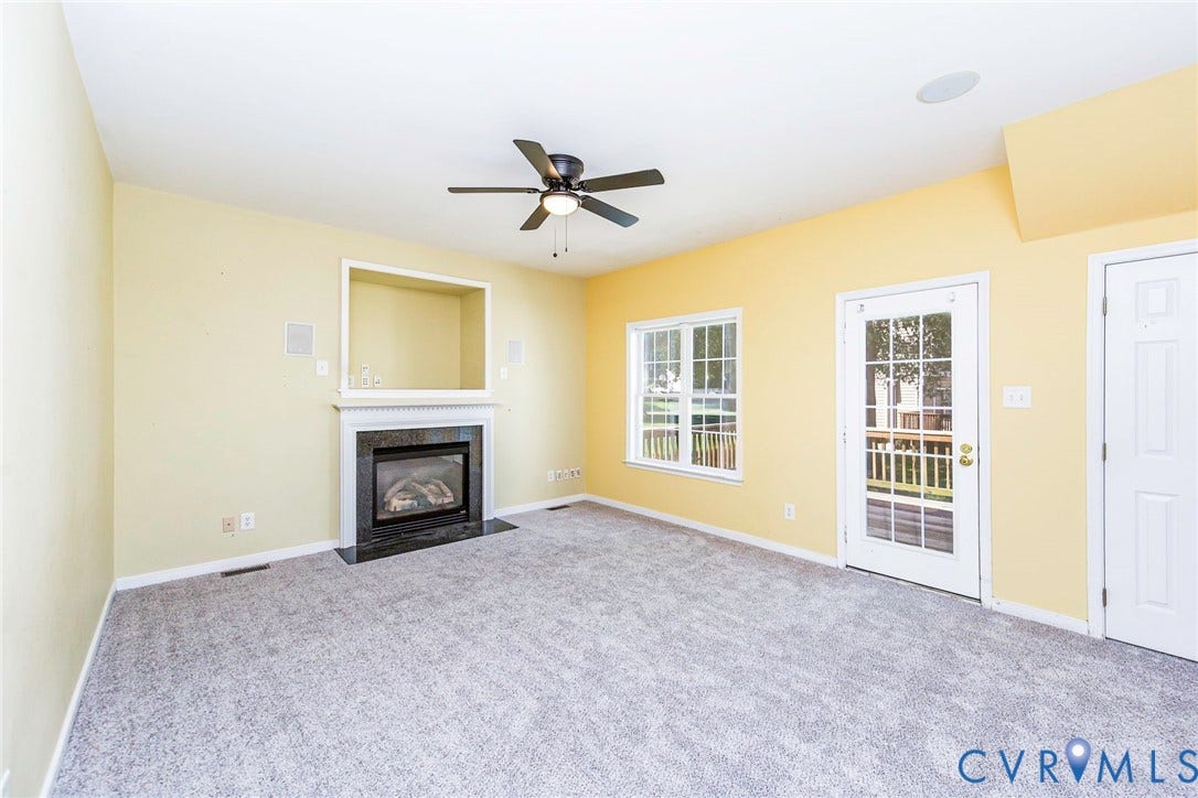 Interior living space featuring light-colored walls, carpet flooring, and a ceiling fan
