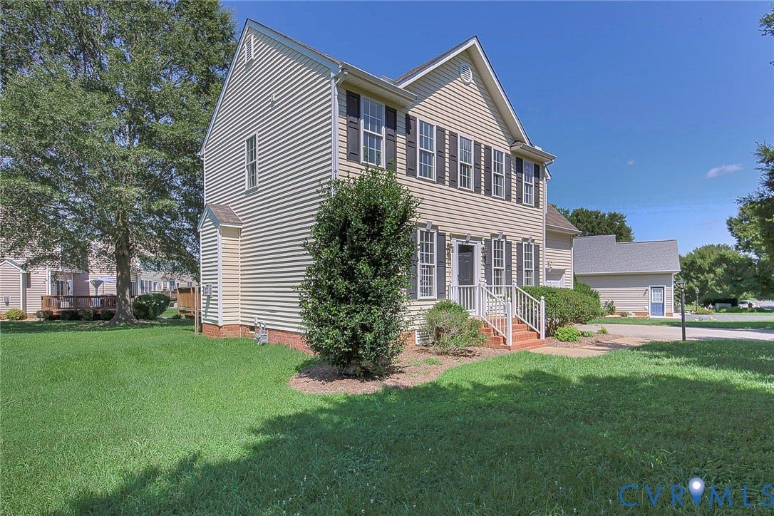 Two-story residence featuring light-colored siding and dark shutters