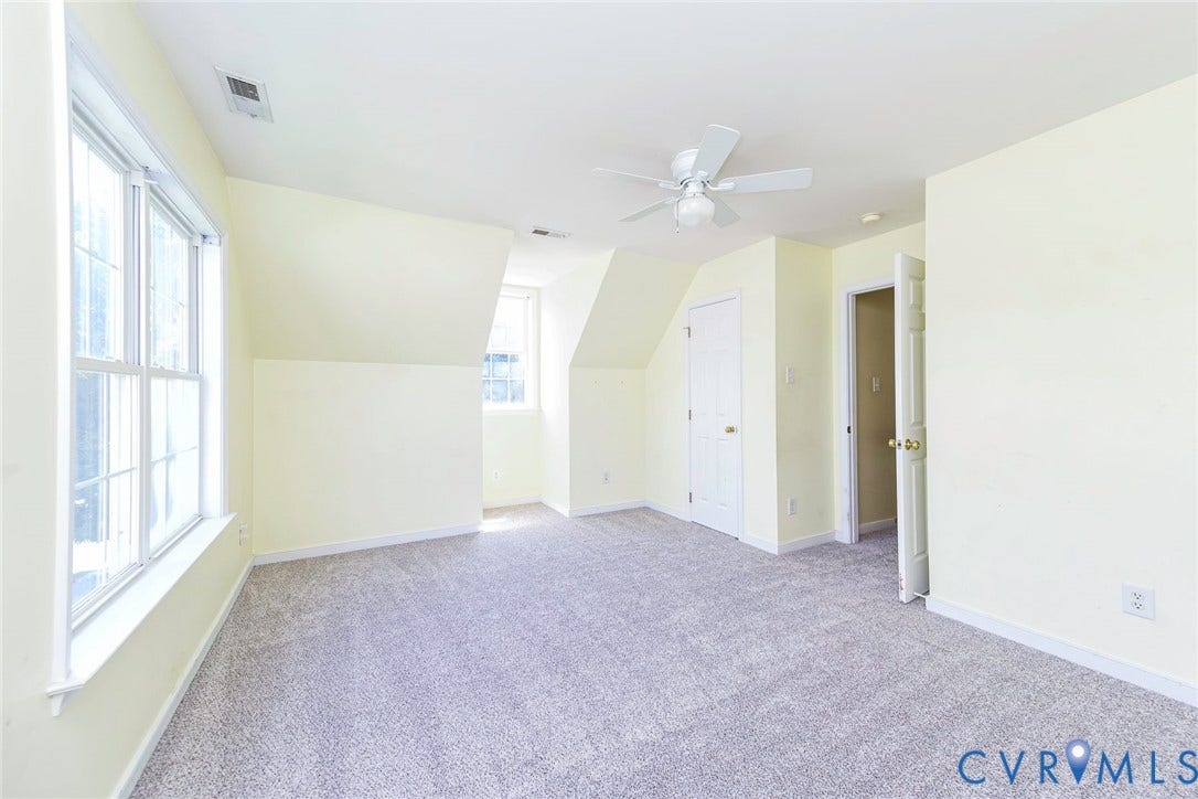 Light-filled room featuring neutral-toned carpet, multiple windows, a ceiling fan, and painted walls