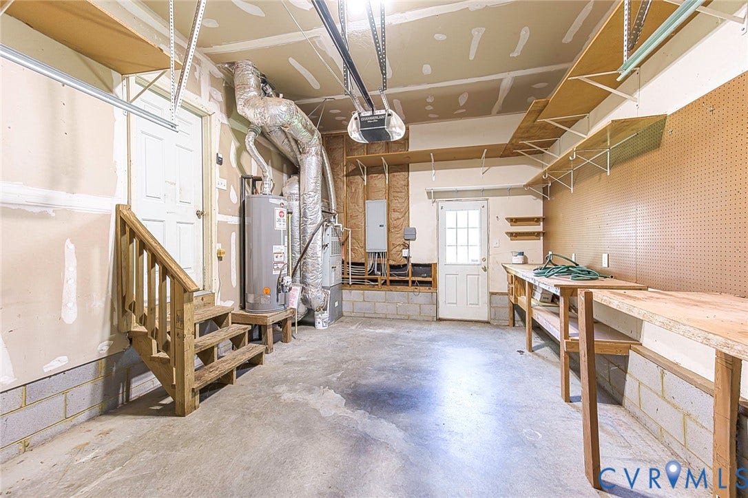 Spacious garage featuring a concrete floor, built-in shelving, two entry doors, and a built-in workbench with pegboard backing