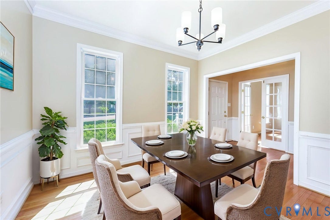 Dining space featuring hardwood flooring, wainscoting, crown molding, and an open entryway to an additional room with French doors