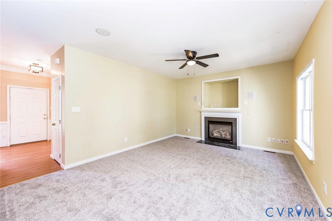 Spacious room featuring light-colored walls and grey carpeting