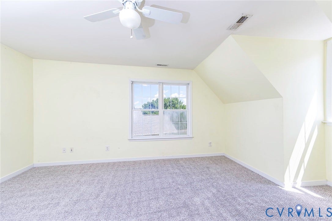 Carpeted room featuring a ceiling fan, recessed lighting, double-hung window, and sloped ceiling details