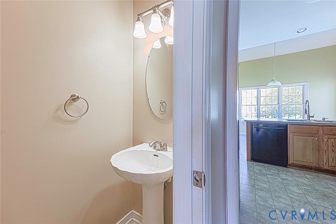 Pedestal sink with an oval mirror and brushed nickel vanity light fixture