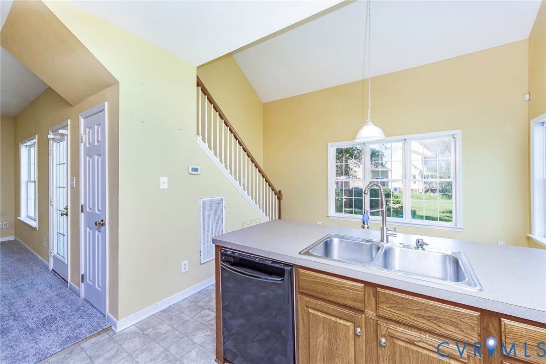 Kitchen island with wood-finish cabinetry, stainless steel double basin sink, and integrated dishwasher