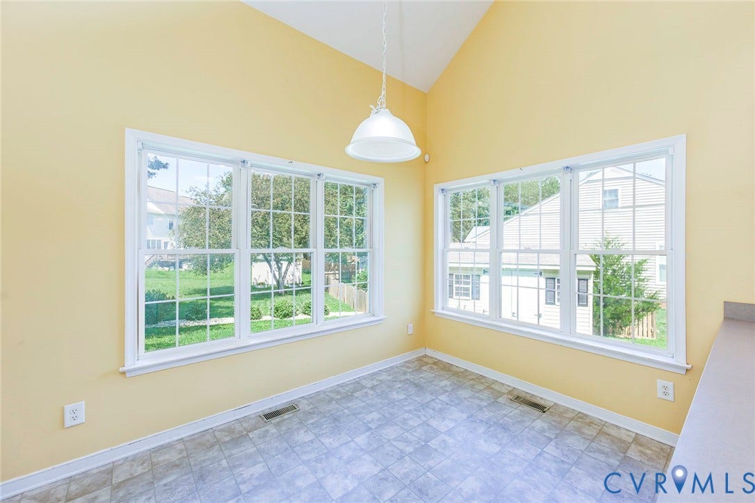 Vaulted ceiling room featuring multiple windows, vinyl flooring, a built-in counter, and a pendant light fixture