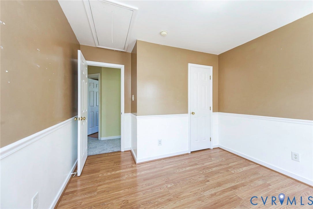 Interior room featuring wood-finish flooring, two-tone walls with white wainscoting, and a white ceiling