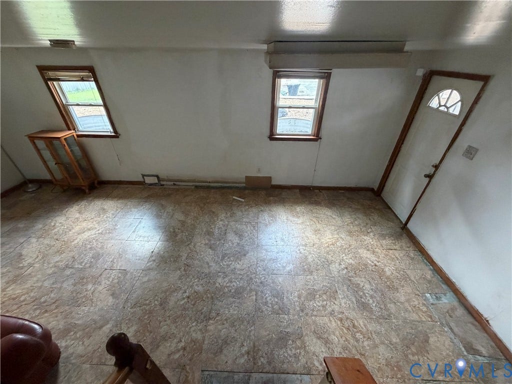 2206 Lancers Boulevard, Richmond, VA 23224 Interior space featuring patterned floor tiles, two windows with wood trim, and a white entry door with a decorative glass insert