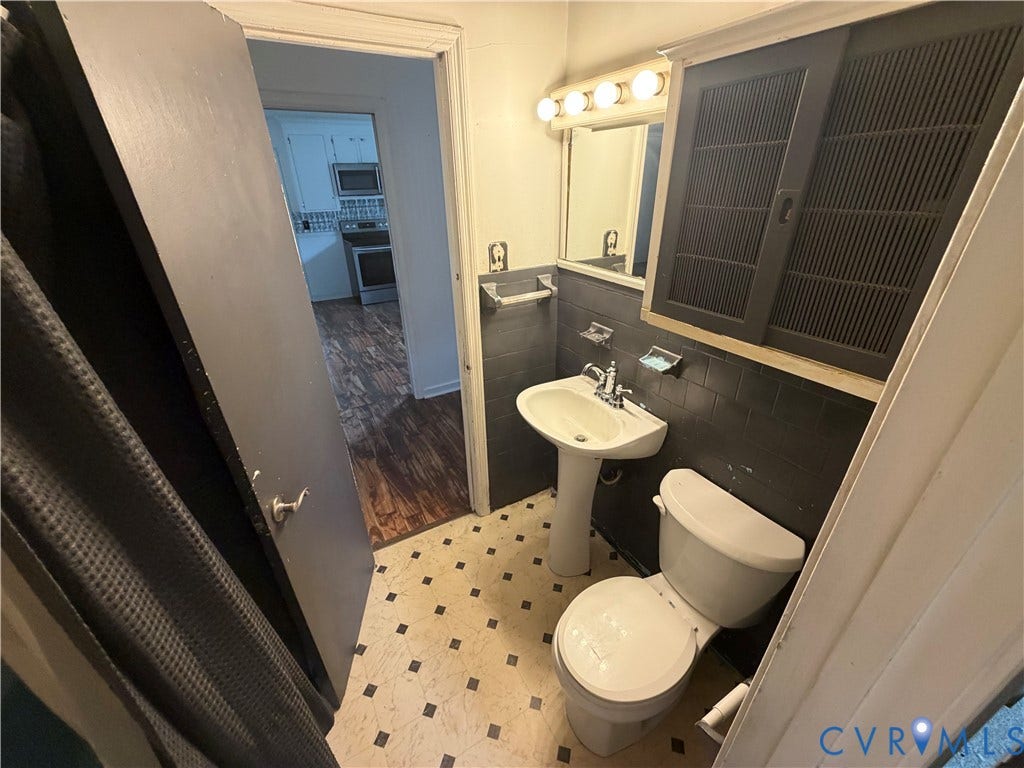 2206 Lancers Boulevard, Richmond, VA 23224 Compact bathroom featuring a pedestal sink, toilet, and black tiled wainscoting