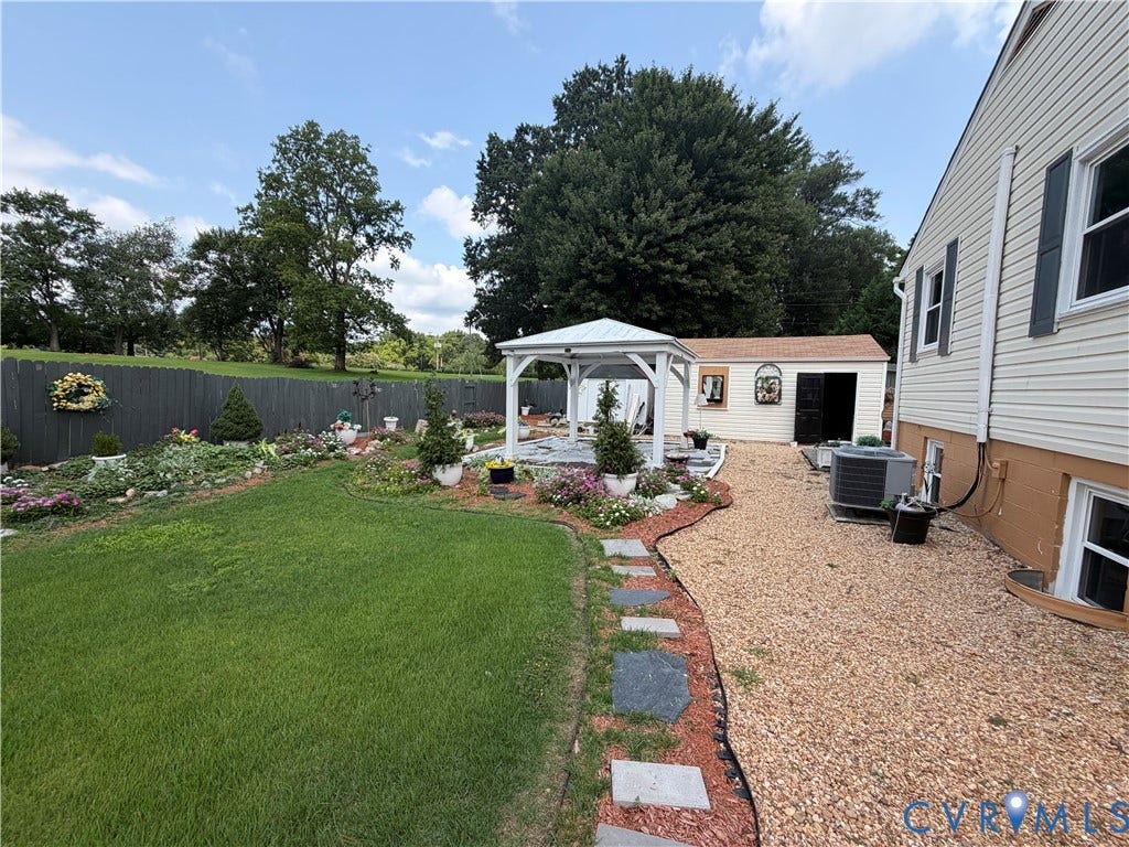 2206 Lancers Boulevard, Richmond, VA 23224 Expansive backyard featuring a white gazebo, manicured lawn, gravel patio, stone pathway, and a detached shed