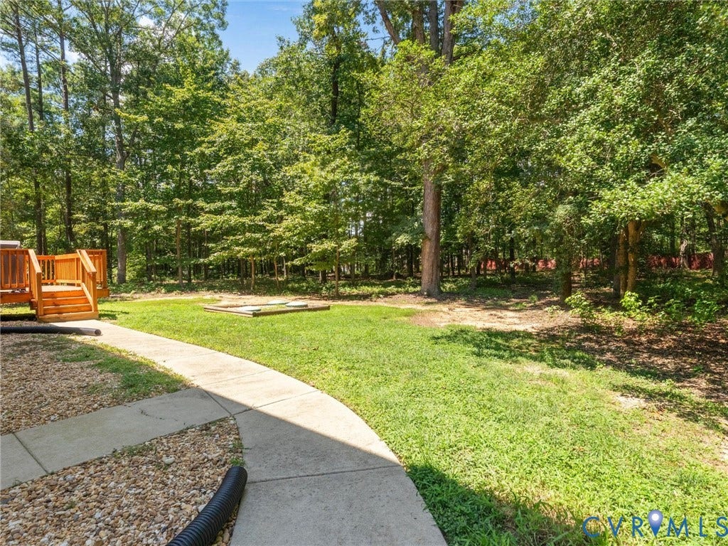 8200 Madeline Court, Strath Woods, Henrico, VA 23231 Expansive backyard featuring a curved concrete pathway, manicured lawn, and mature trees