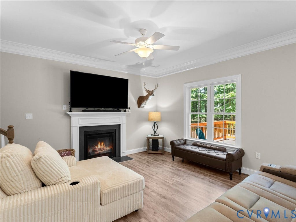 8200 Madeline Court, Strath Woods, Henrico, VA 23231 Living area featuring wood-finish flooring, a fireplace with a white mantel, and a ceiling fan
