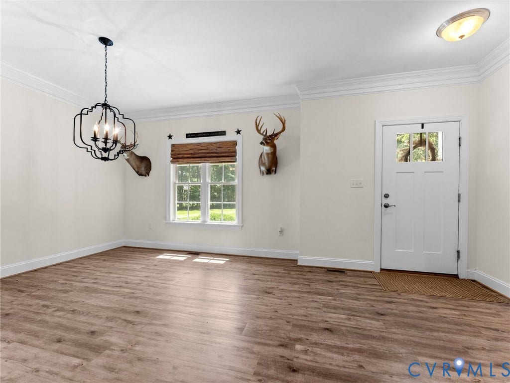 8200 Madeline Court, Strath Woods, Henrico, VA 23231 Spacious room featuring wood-finish flooring, white trim, and a decorative chandelier