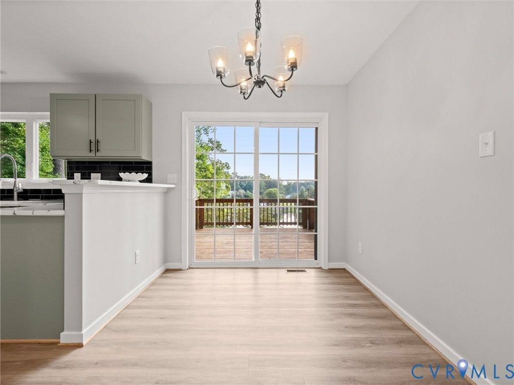 2224 Highland Drive, Powhatan, VA 23139 Light wood-finish flooring, glass-paned sliding door, black subway tile backsplash, and a black wrought iron chandelier with clear glass shades