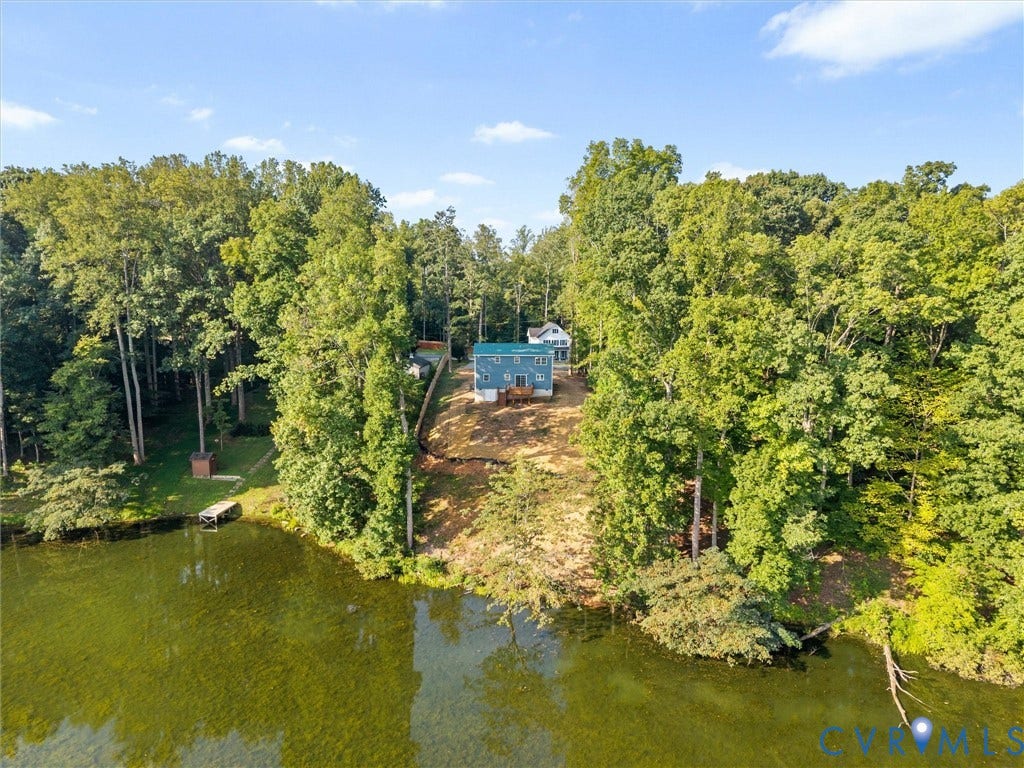 2224 Highland Drive, Powhatan, VA 23139 Lakefront property featuring a private dock, mature tree surround, and a light blue exterior