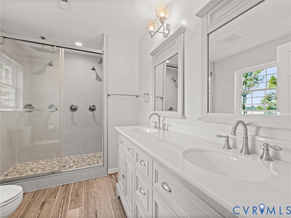 2224 Highland Drive, Powhatan, VA 23139 Dual-sink vanity with a white countertop and brushed nickel fixtures, complemented by two framed mirrors