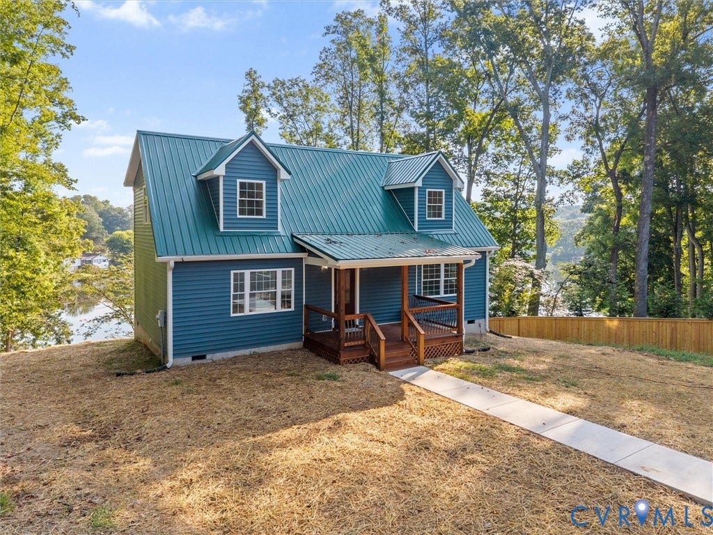 2224 Highland Drive, Powhatan, VA 23139 Blue siding exterior featuring a green metal roof, a covered porch with wood railings, and multiple dormer windows