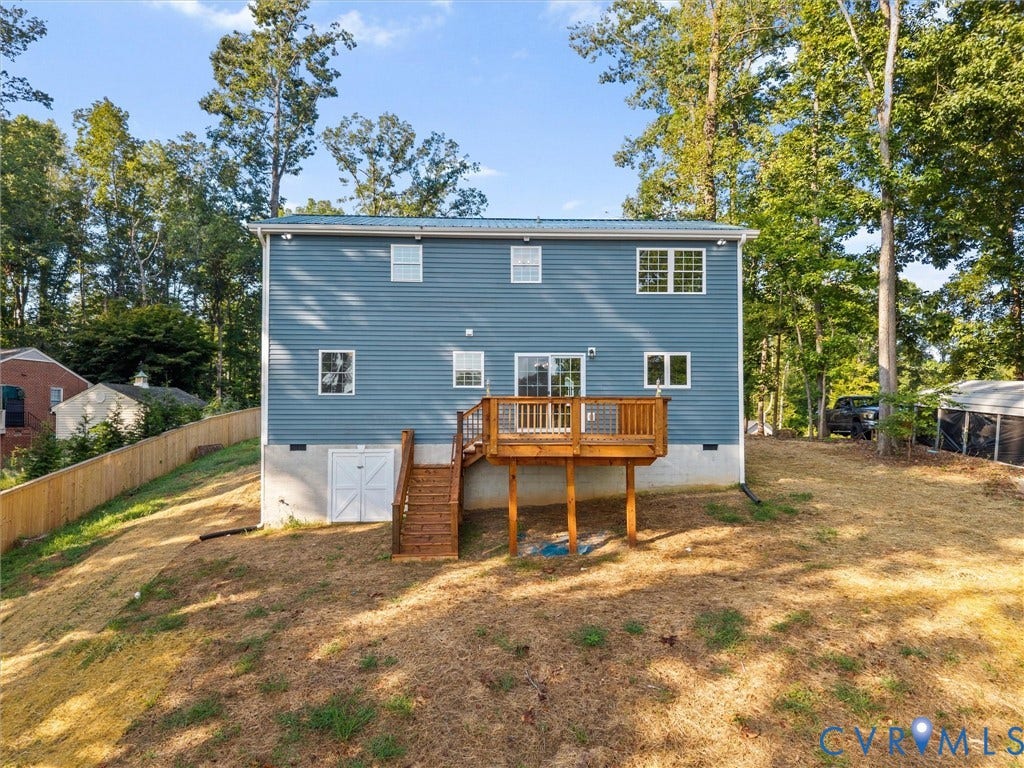 2224 Highland Drive, Powhatan, VA 23139 Blue siding exterior with a metal roof, featuring a wooden deck with railing, sliding glass doors, and a ground-level storage door