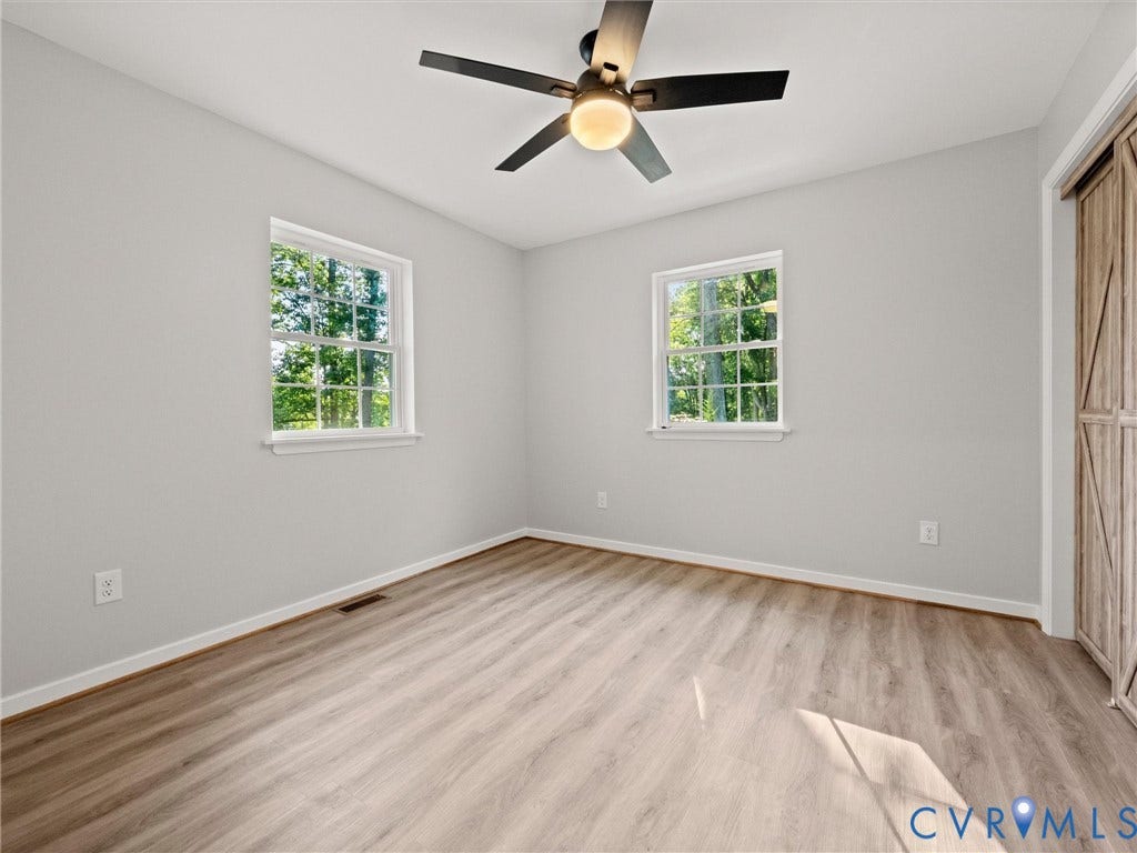 2224 Highland Drive, Powhatan, VA 23139 Wood-finish flooring, two windows with white trim, a ceiling fan with integrated lighting, and a wood-finish barn door