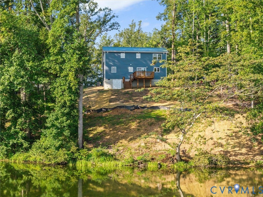 2224 Highland Drive, Powhatan, VA 23139 Blue siding exterior with a metal roof, featuring a wood-finish deck and surrounding mature trees