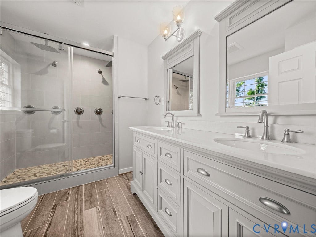 2224 Highland Drive, Powhatan, VA 23139 Dual vanity with undermount sinks, wood-finish flooring, glass-enclosed shower with pebble-tiled floor, and dual shower heads