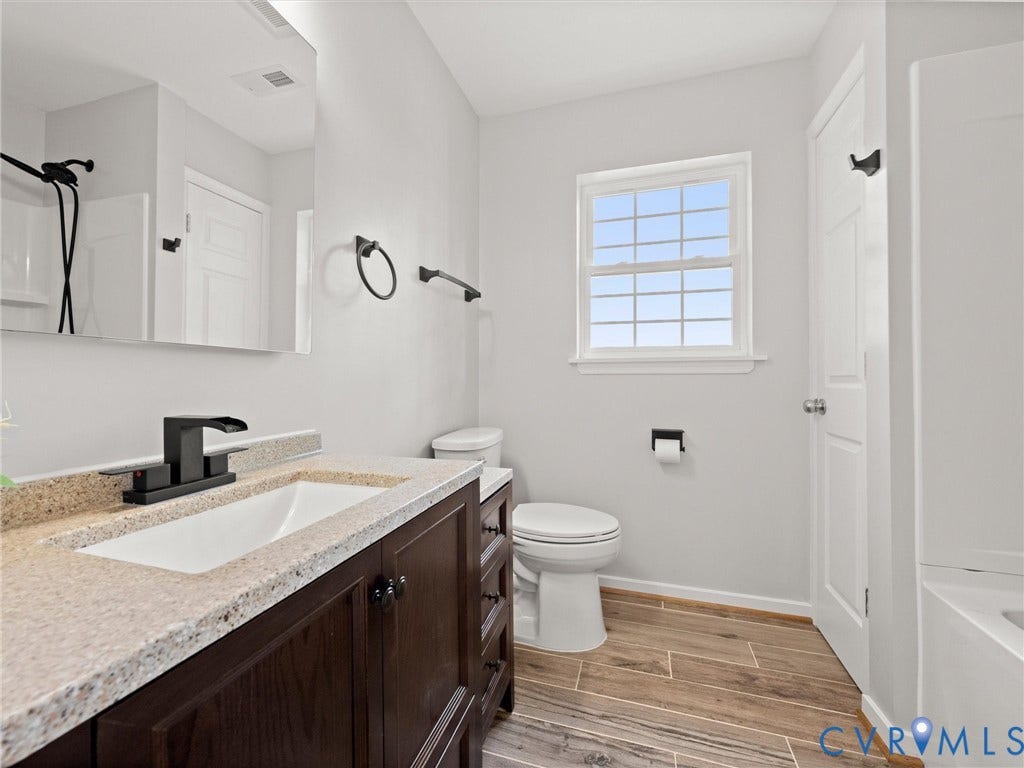 2224 Highland Drive, Powhatan, VA 23139 Wood-finish tile flooring, dark wood vanity with ample storage, integrated basin with light-toned countertop, and matte black fixtures