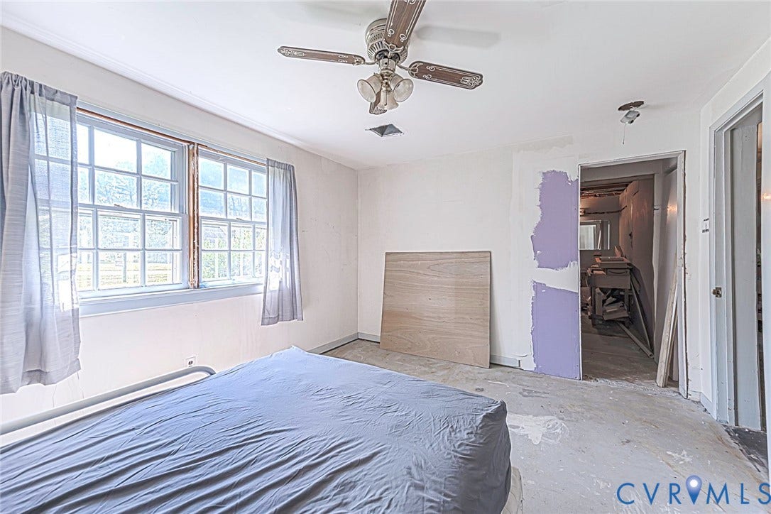 124 Northfield Lane, North Chesterfield, VA 23236 Spacious primary bedroom with abundant natural light from large multi-pane windows, ceiling fan with integrated lighting, wood-finish flooring, and direct access to ensuite bathroom