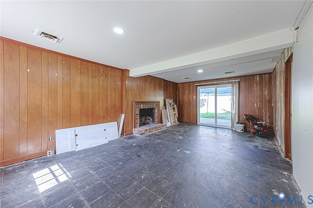 124 Northfield Lane, North Chesterfield, VA 23236 Spacious room featuring warm wood-paneled walls, slate-finish flooring, recessed lighting, a wood-burning fireplace, and glass sliding doors providing natural light and access to outdoor space