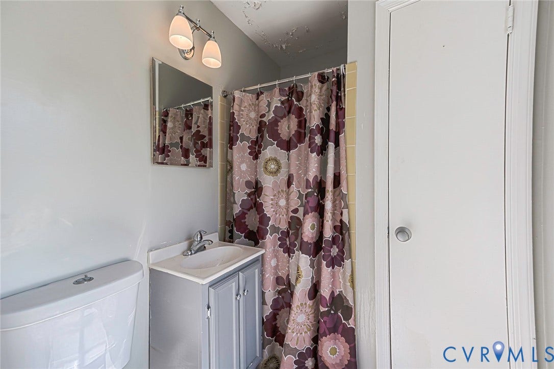 124 Northfield Lane, North Chesterfield, VA 23236 Bathroom featuring a white vanity with integrated sink, floral patterned shower curtain, overhead lighting fixture, and convenient access to adjacent spaces through white panel doors