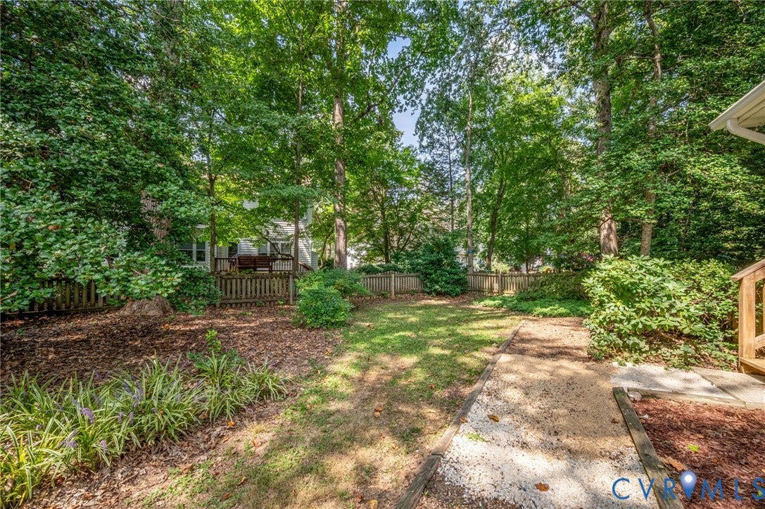 3704 Milbrier Place, Henrico, VA 23233 Expansive backyard with mature trees, a wooden fence, and a gravel pathway