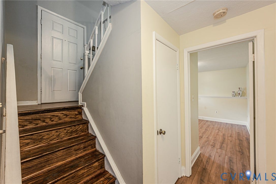 9406 Emmett Court, Glen Allen, VA 23060 Rich wood-finish staircase with white risers and railing, leading to a paneled entry door