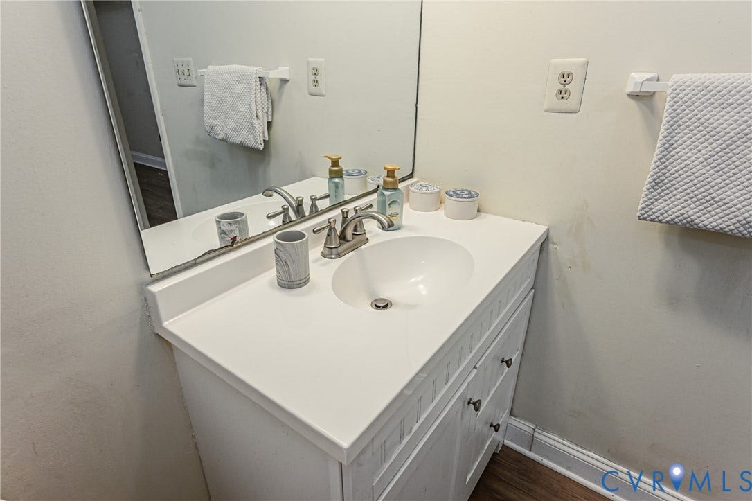 9406 Emmett Court, Glen Allen, VA 23060 Clean and functional bathroom vanity featuring a white cabinetry base with ample storage, a white quartz countertop with integrated sink, brushed nickel faucet with dual handles, and a large framed mirror