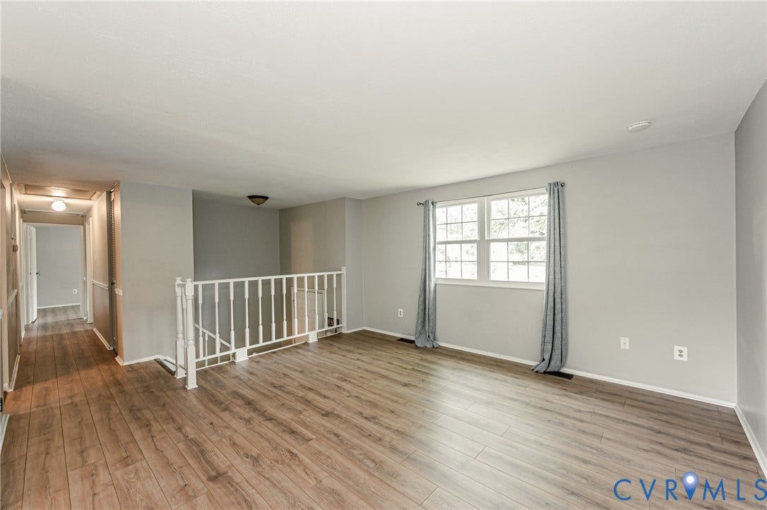 9406 Emmett Court, Glen Allen, VA 23060 Spacious loft-style room featuring wood-finish flooring throughout, abundant natural light from large multi-pane windows with custom drapery hardware, white interior railing system, and neutral wall finishes