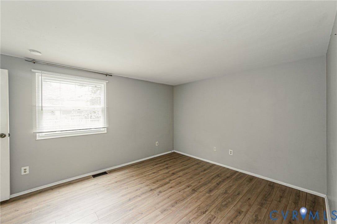 9406 Emmett Court, Glen Allen, VA 23060 Spacious bedroom featuring wood-finish flooring, neutral wall finishes, and abundant natural light from a large window with blinds