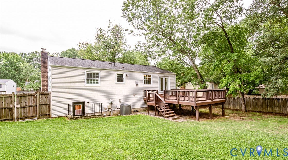 9406 Emmett Court, Glen Allen, VA 23060 Spacious backyard retreat featuring a manicured lawn, mature tree canopy, and composite deck with railings