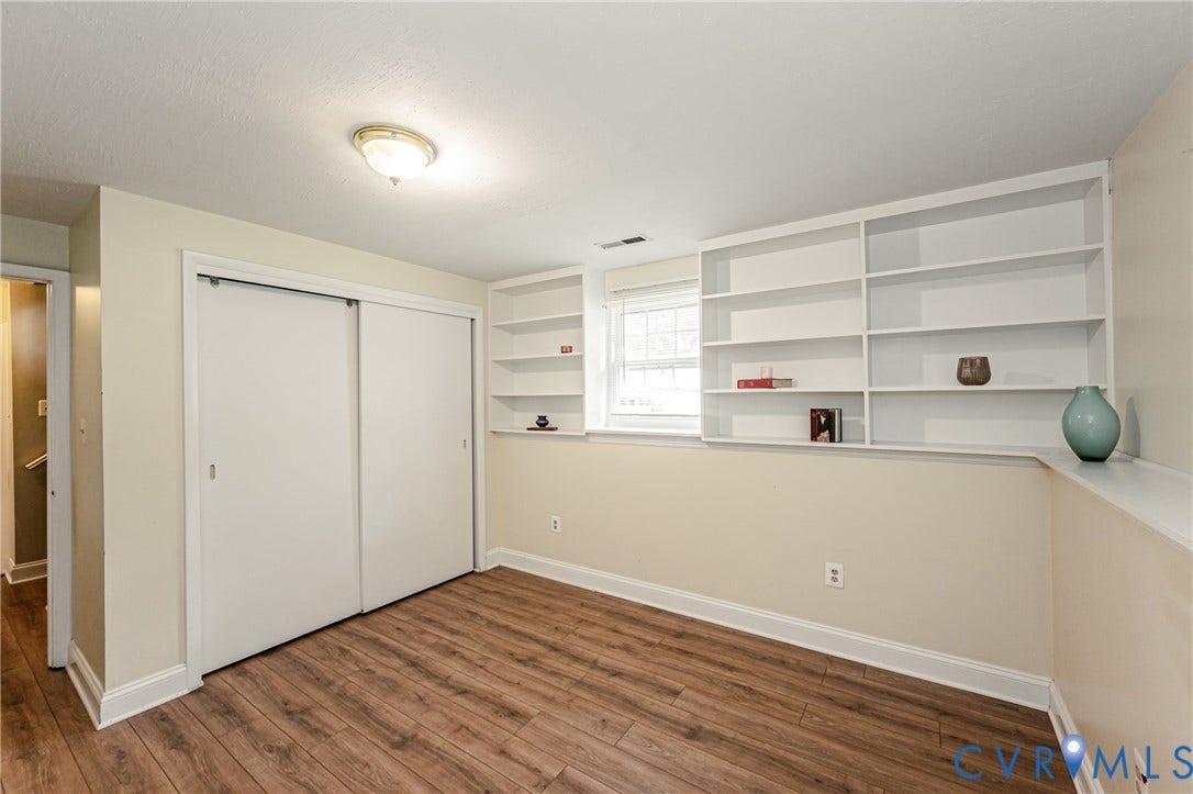 9406 Emmett Court, Glen Allen, VA 23060 Room featuring built-in shelving, wood-finish flooring, a window, and a closet with sliding doors