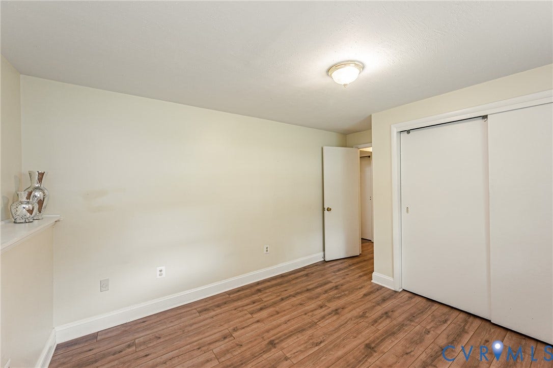 9406 Emmett Court, Glen Allen, VA 23060 Spacious bedroom showcasing warm wood-finish flooring, fresh neutral walls, and abundant natural light from recessed ceiling fixture