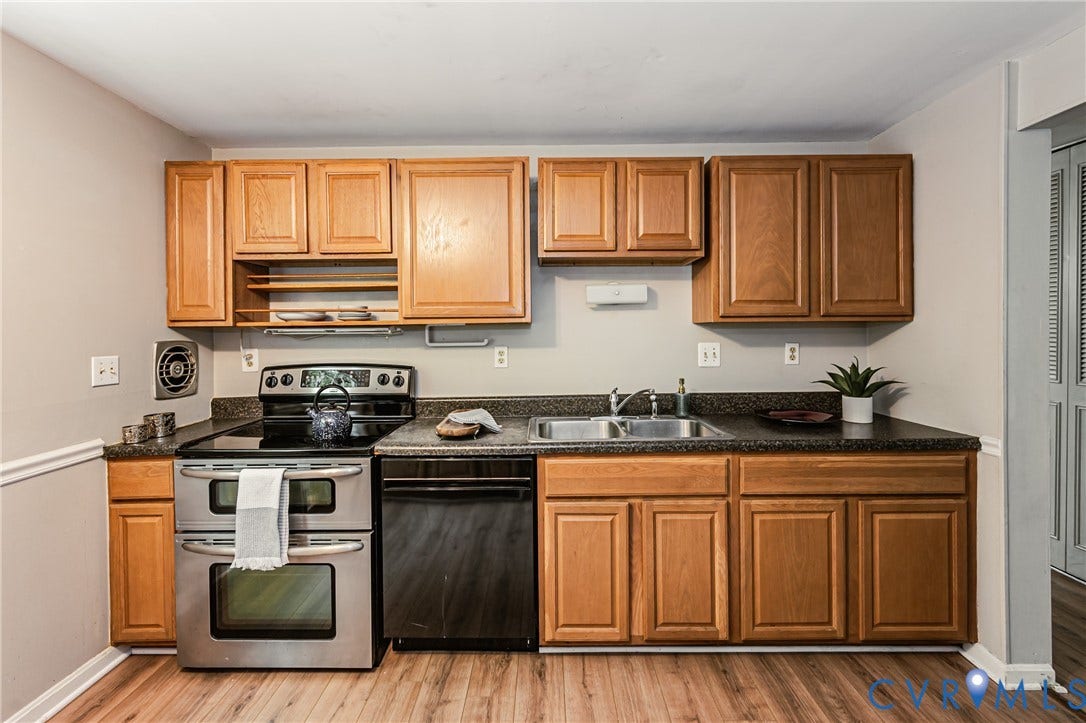 9406 Emmett Court, Glen Allen, VA 23060 Galley kitchen featuring stainless steel appliances, including dual ovens and a five-burner cooktop, paired with wood-finish cabinetry and black countertops