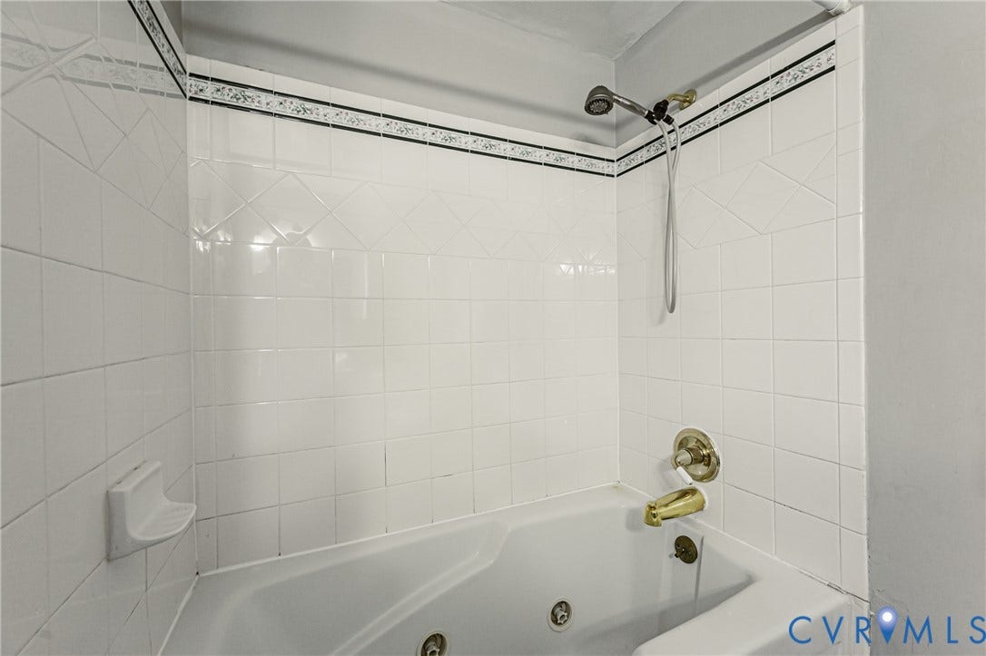 9406 Emmett Court, Glen Allen, VA 23060 Clean and functional bathroom featuring white subway tile walls, a chrome showerhead with adjustable fixtures, and a soaking tub with brass valve hardware