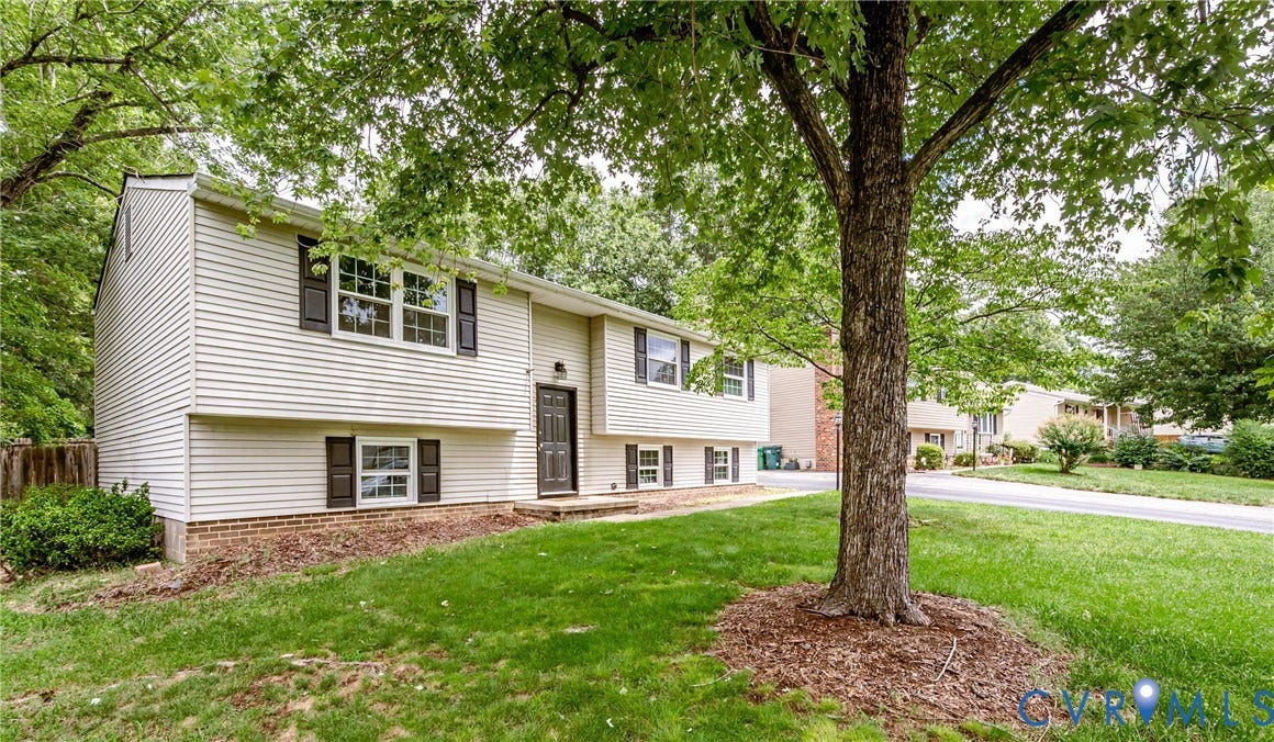 9406 Emmett Court, Glen Allen, VA 23060 Two-story colonial with white vinyl siding and brick accents, set on a mature landscaped lot featuring a large shade tree, mulched planting beds, and level lawn