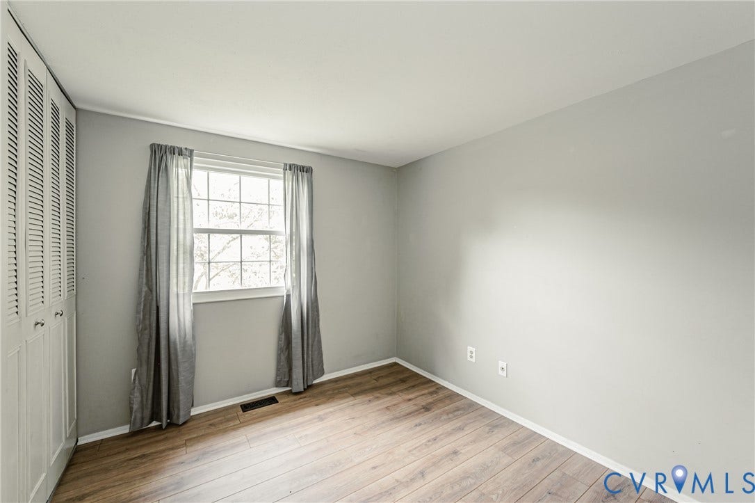 9406 Emmett Court, Glen Allen, VA 23060 Bright bedroom offering hardwood flooring, large window with natural light, closet with louvered doors, and neutral wall finishes