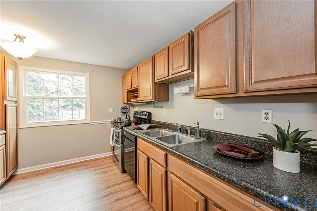 9406 Emmett Court, Glen Allen, VA 23060 Galley-style kitchen featuring warm wood-finish cabinetry, dark granite countertops, and stainless steel appliances including a gas range